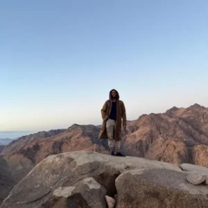 Traveler standing on a mountain peak experiencing spiritual awakening and meditation in Sinai Egypt