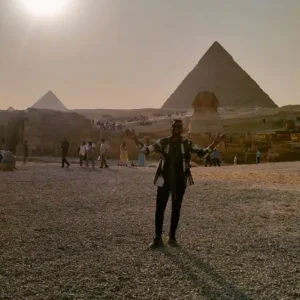 Male tourist embracing the cosmic energy with open arms at Giza Pyramids and Sphinx in Egypt