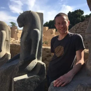Traveler wearing a flower of life shirt connecting with Sekhmet statue energy at Karnak Temple Luxor.