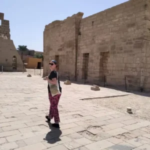 Woman walking through the stone courtyard of an ancient Egyptian temple during a wellness retreat